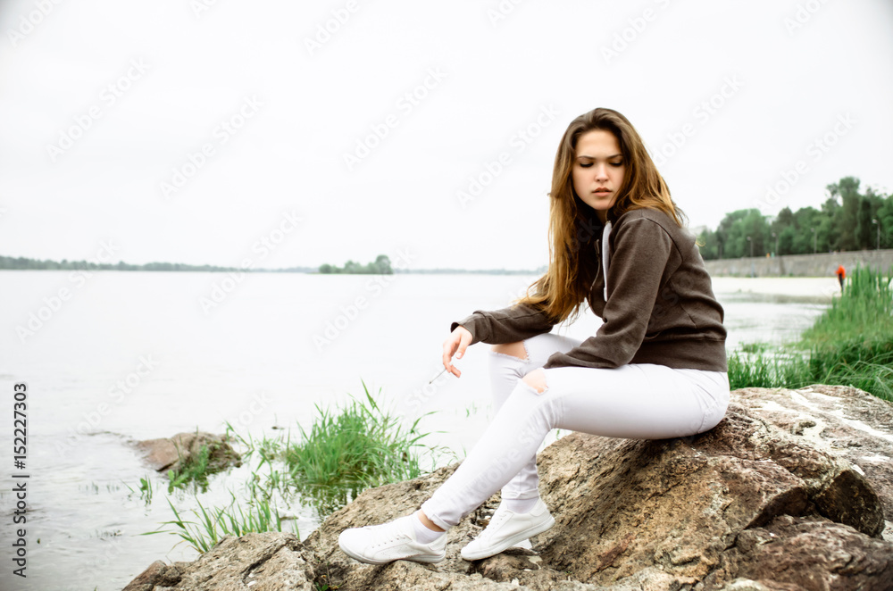girl sits on the rocks, girl with a cigarette