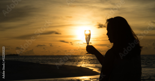 female silhouette with wine on sunset