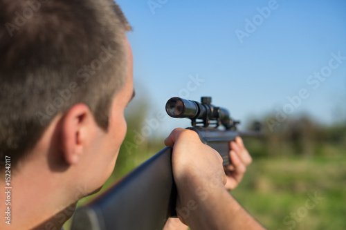 The man takes aim at the target with a retro sniper rifle. Selective Focus. Warm summer day