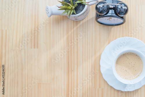Clock and coffee cup on wooden table top view