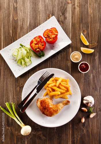 Roast chicken leg with french fries on wooden table