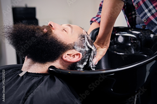 Hairdresser washing bearded men's hair.