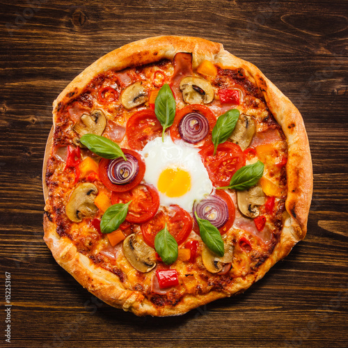 Pizza with egg and mushrooms on wooden table