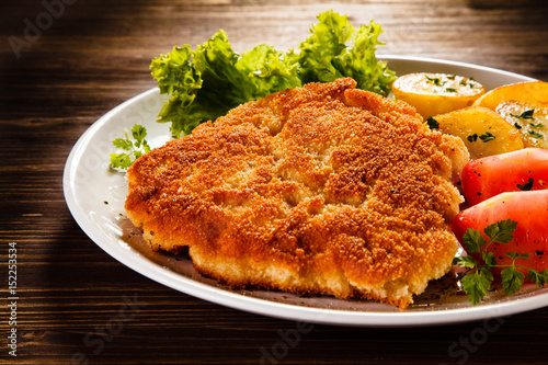 Fried pork chop with potatoes on wooden table