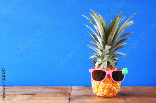 Pineapple with sunglasses on the table. Beach and tropical theme.