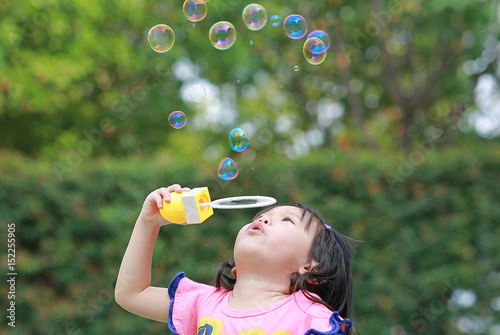 Cute little girl playing bubble in the park.