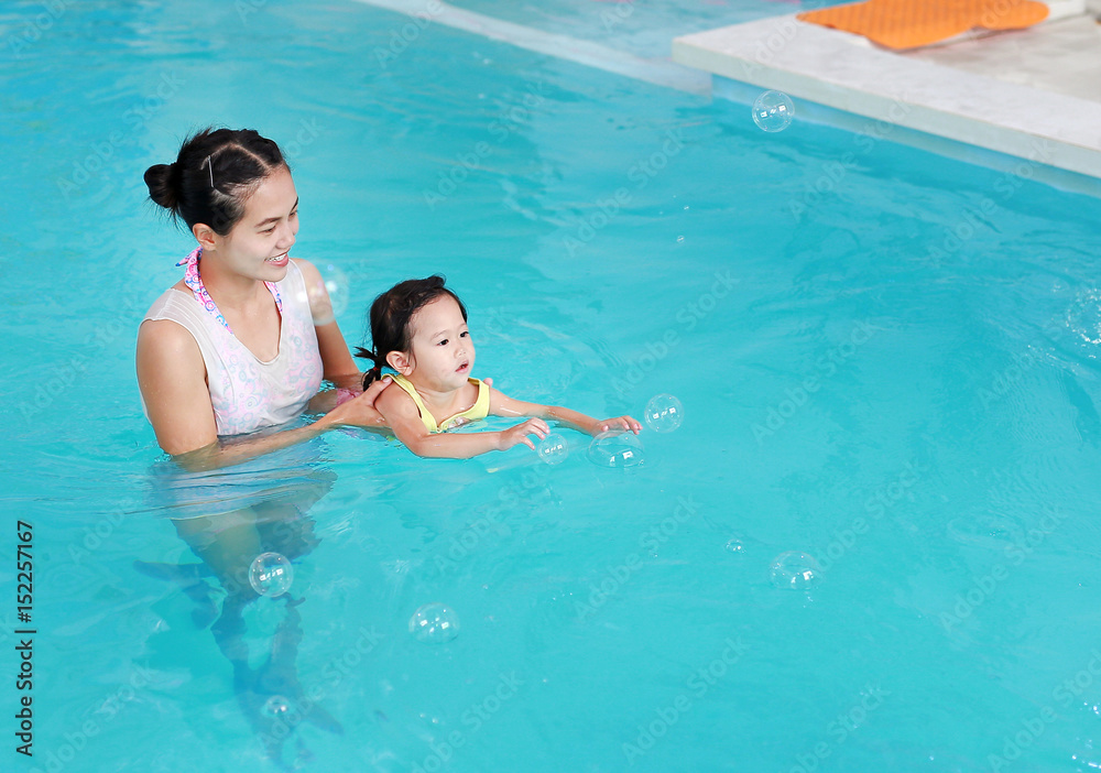 Close up mother teaching kid in swimming pool.