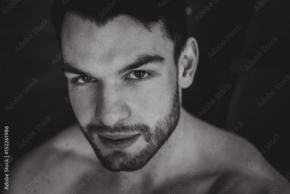 Portrait of young attractive man with muscular strong black beard, piercing sexy look in the studio posing Portrait of young attractive man with muscular strong black beard, piercing sexy look in the studio posing