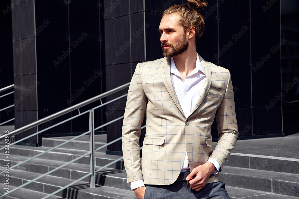portrait of sexy handsome fashion male model man dressed in elegant beige checkered suit .posing near dark blue wall in the street background portrait of sexy handsome fashion male model man dressed in elegant beige checkered suit .posing near dark blue wall in the street background