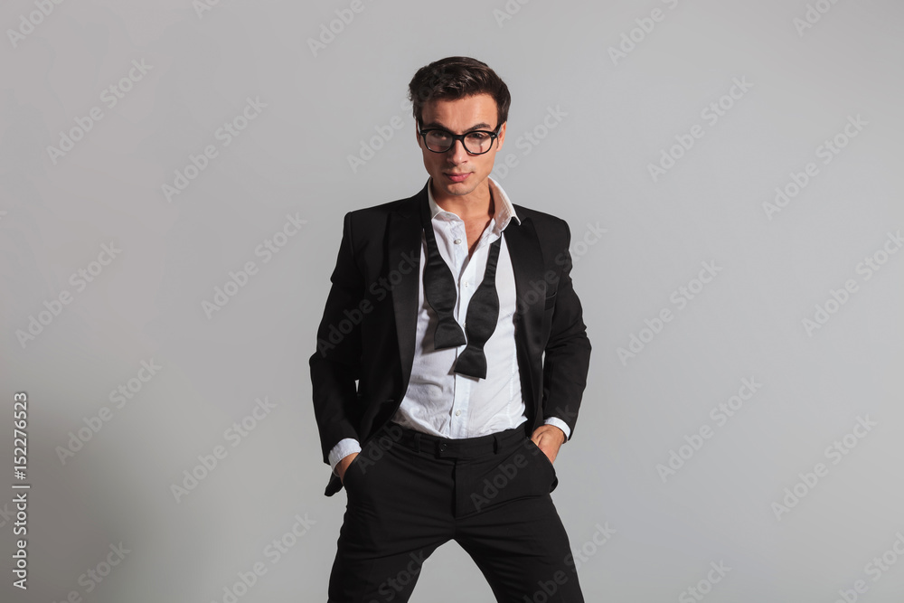 relaxed young man in tuxedo standing with hands in pockets relaxed young man in tuxedo standing with hands in pockets