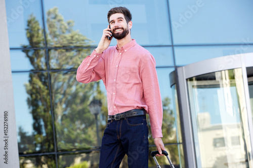 handsome man smiling and talking on mobile phone outside
