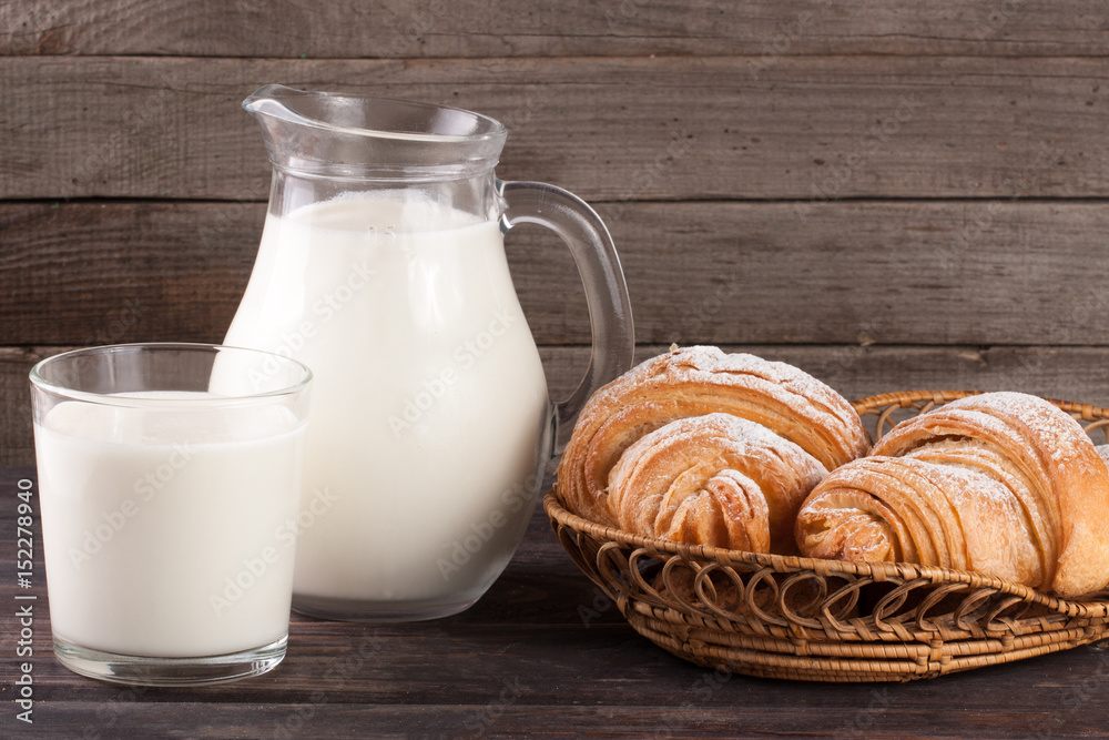 jug and glass of milk with croissants on a wooden background jug and glass of milk with croissants on a wooden background