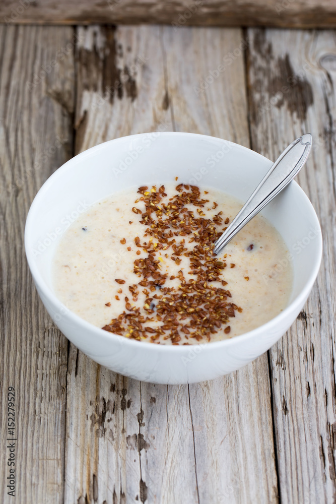 Fresh cooked oatmeal porridge with crushed linseed. On wooden table. Natural light, selective focus. Fresh cooked oatmeal porridge with crushed linseed. On wooden table. Natural light, selective focus.