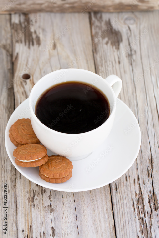 Fresh brewed coffee and cookies. On wooden table. Natural light, selective focus. 