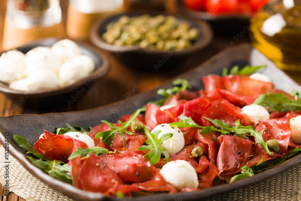 Beef carpaccio served with balls of mozzarella cheese, arugula and capers. Beef carpaccio served with balls of mozzarella cheese, arugula and capers.