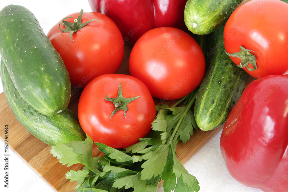 tomatoes, peppers ,cucumbers and parsley on a cutting Board