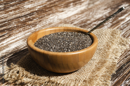 Close up of chia seeds (Salvia hispanica) in wooden bowl on a rustic table. This superfood is a rich in omega-3 fatty acids, essential for good health. Healthy eating , vegan diet concept.