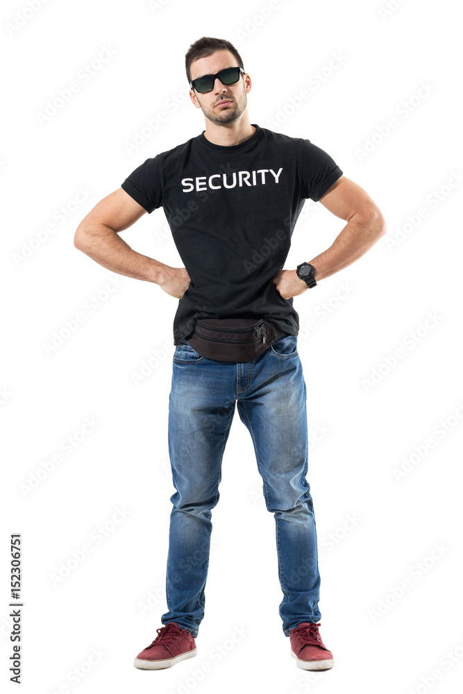 Serious macho bouncer or undercover officer with hands on hips looking at camera. Full body length portrait isolated on white studio background. Serious macho bouncer or undercover officer with hands on hips looking at camera. Full body length portrait isolated on white studio background.
