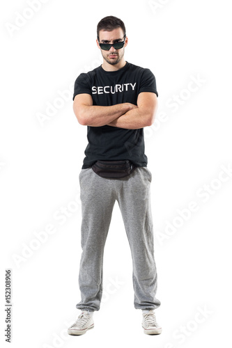 Tough serious bouncer or bodyguard with crossed arms staring at camera. Full body length portrait isolated on white studio background. 