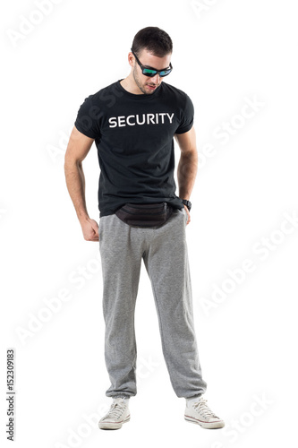 Sporty man with sunglasses and fanny pack waist back looking down. Full body length portrait isolated on white studio background. 