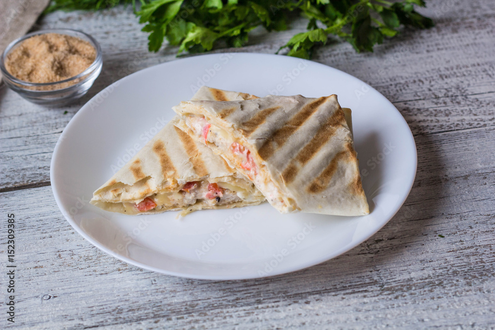 shawarma in thin pita bread with chicken and vegetables on a plate shawarma in thin pita bread with chicken and vegetables on a plate