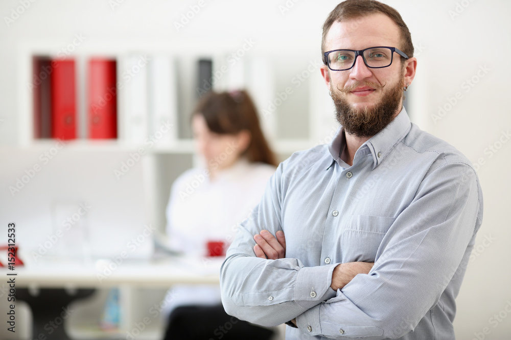 A man with arms crossed stands on the background of the office. Concept: teamwork