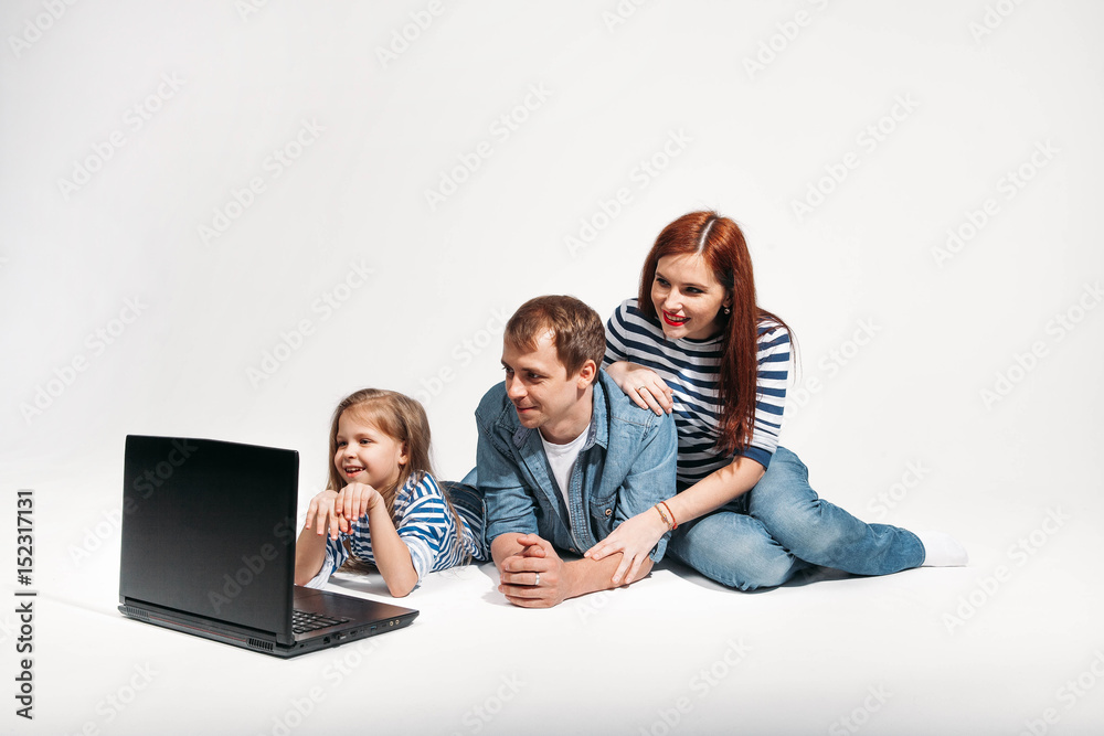 Happy family Father, mother and child lying on the floor with laptop on white background isolated Happy family Father, mother and child lying on the floor with laptop on white background isolated