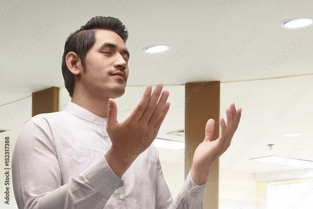 Young asian muslim man in traditional dress praying Young asian muslim man in traditional dress praying