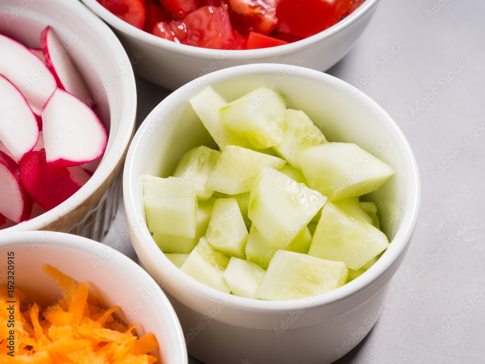 Mix of vegetable bowls for salad or snacks on gray background. Diet detox concept. Cook with cucumbers Mix of vegetable bowls for salad or snacks on gray background. Diet detox concept. Cook with cucumbers