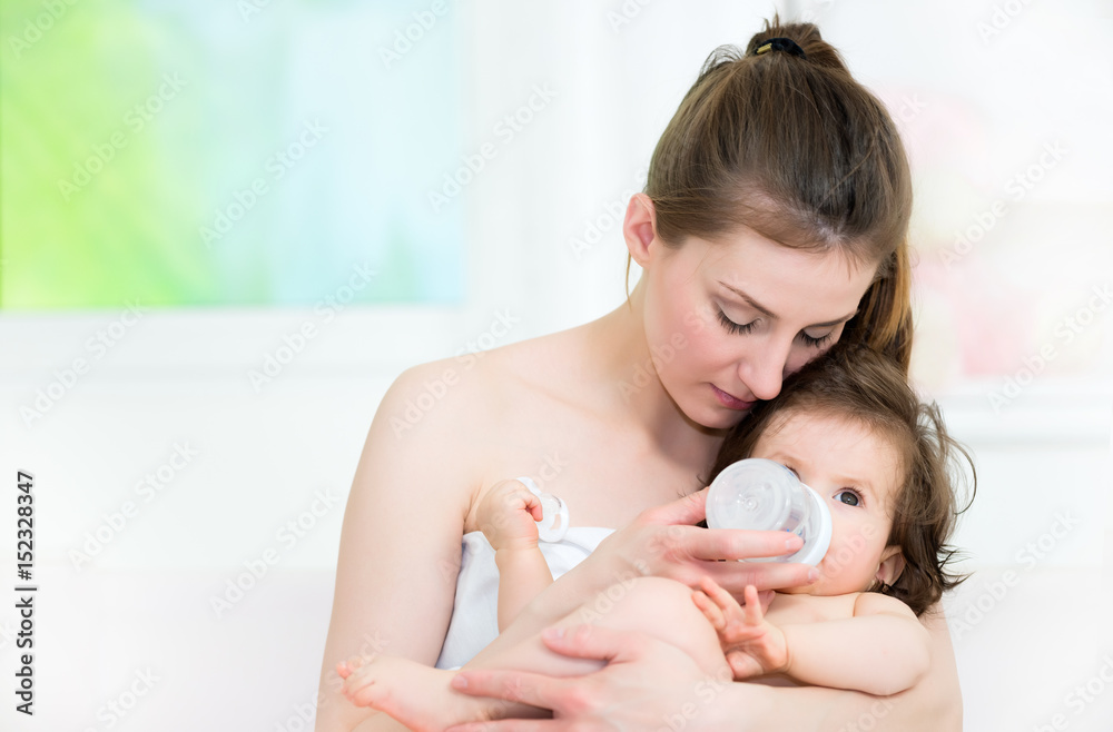 Mom and baby in a hug, baby drinking a milk from the baby bottle.Shallow doff Mom and baby in a hug, baby drinking a milk from the baby bottle.Shallow doff