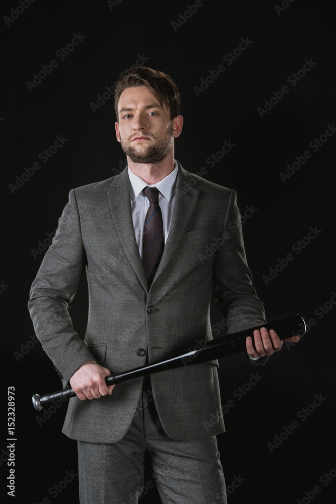 Serious young businessman holding baseball bat and looking at camera Serious young businessman holding baseball bat and looking at camera