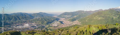 Drone aerial view to the Seriana valley in a clear and blue day. Fog is covering the villages. Panorama from Farno Mountain, Bergamo, Italy.  photo