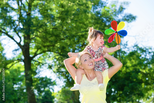 Mom and little daughter have a fun outdoors with a pinwheel toy.Copy space