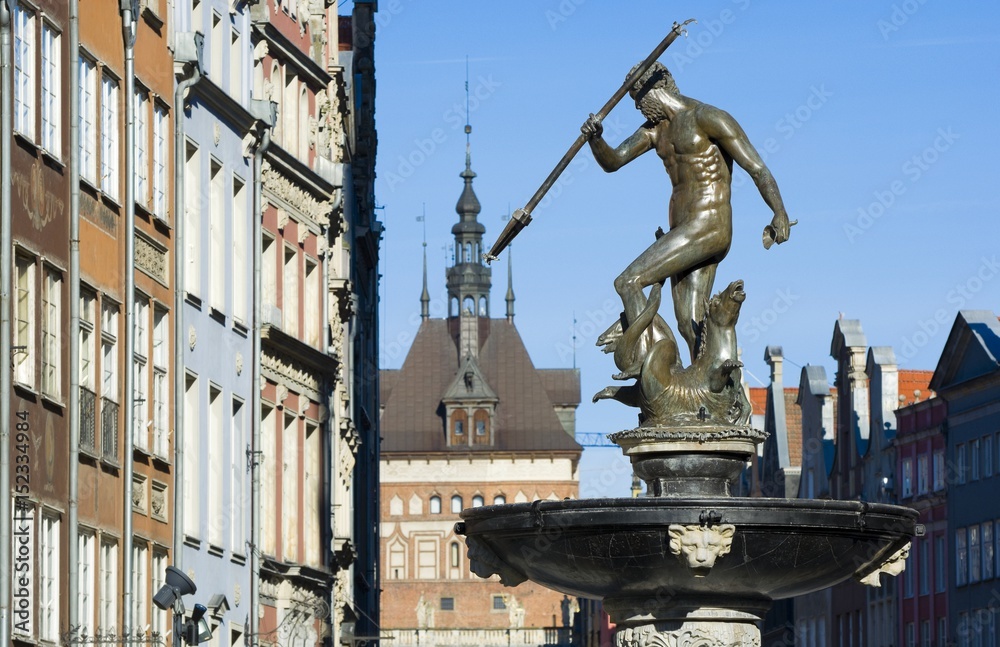 Fototapeta premium Neptune Fountain - symbol of Gdansk, located at Long Market, blurred Prison Tower and burgher houses in the background, Poland