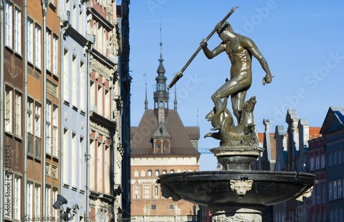 Neptune Fountain - symbol of Gdansk, located at Long Market, blurred Prison Tower and burgher houses in the background, Poland