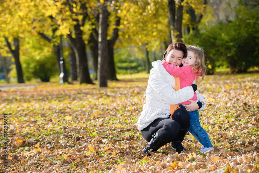 Hugging mother and daughter in autumn park.Copy space Hugging mother and daughter in autumn park.Copy space