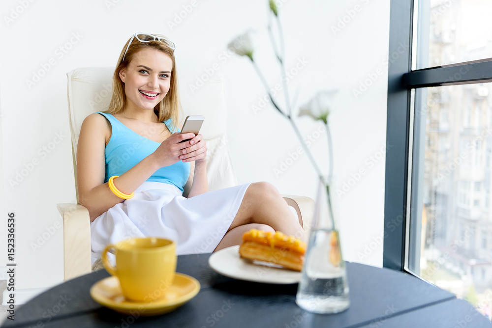 Happy young woman writing messages by phone