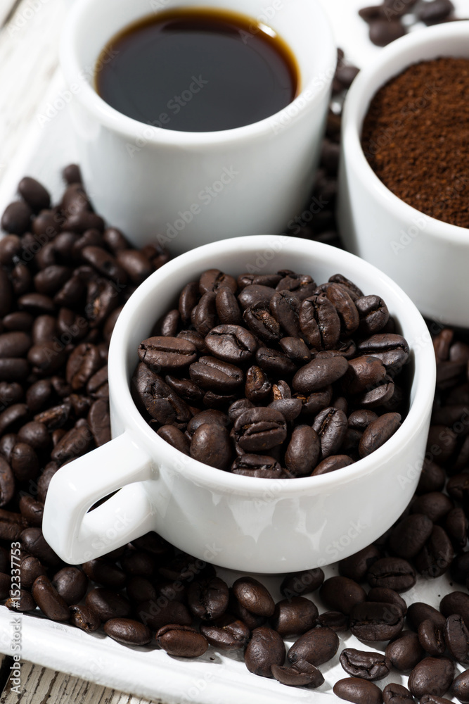 Three types of coffee - ground, grain and beverage in white cups