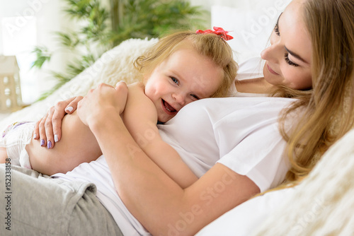 Loving toddler hugging her parent on bed