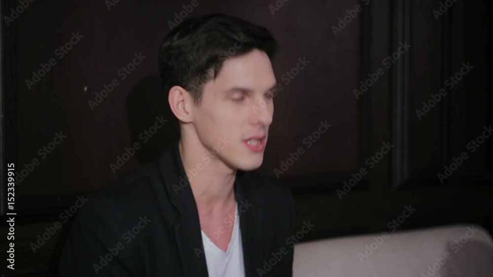 Young attractive charismatic guy sitting on the couch actively gesturing during conversation Young attractive charismatic guy sitting on the couch actively gesturing during conversation