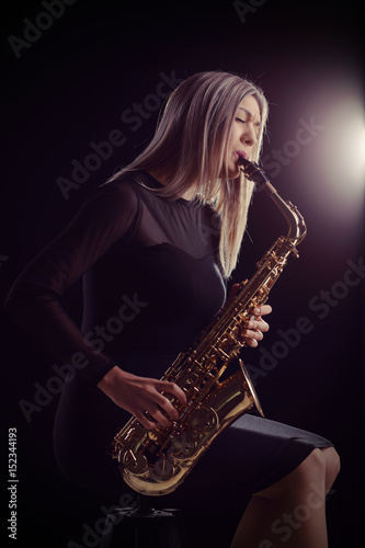 Photography Female jazz musician sitting on chair and playing saxophone