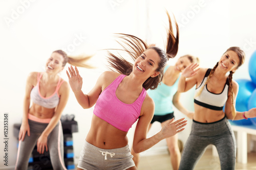Group of happy people with coach dancing in gym photo