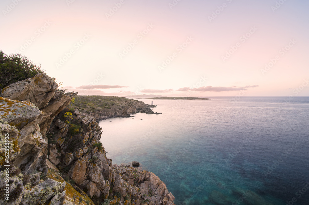 Seascape of the Italian coast at sunset with a lighthouse in the background. Porto Cervo - Emerald coast, Sardinia - Italy