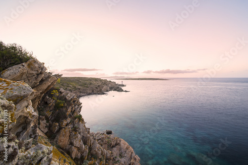 Seascape of the Italian coast at sunset with a lighthouse in the background. Porto Cervo - Emerald coast, Sardinia - Italy