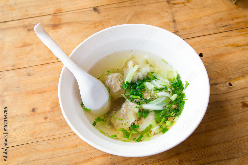 Wonton soup with spoon in a bowl. Traditional asian food Wonton soup with spoon in a bowl. Traditional asian food