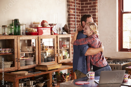 Young white couple hugging in their kitchen