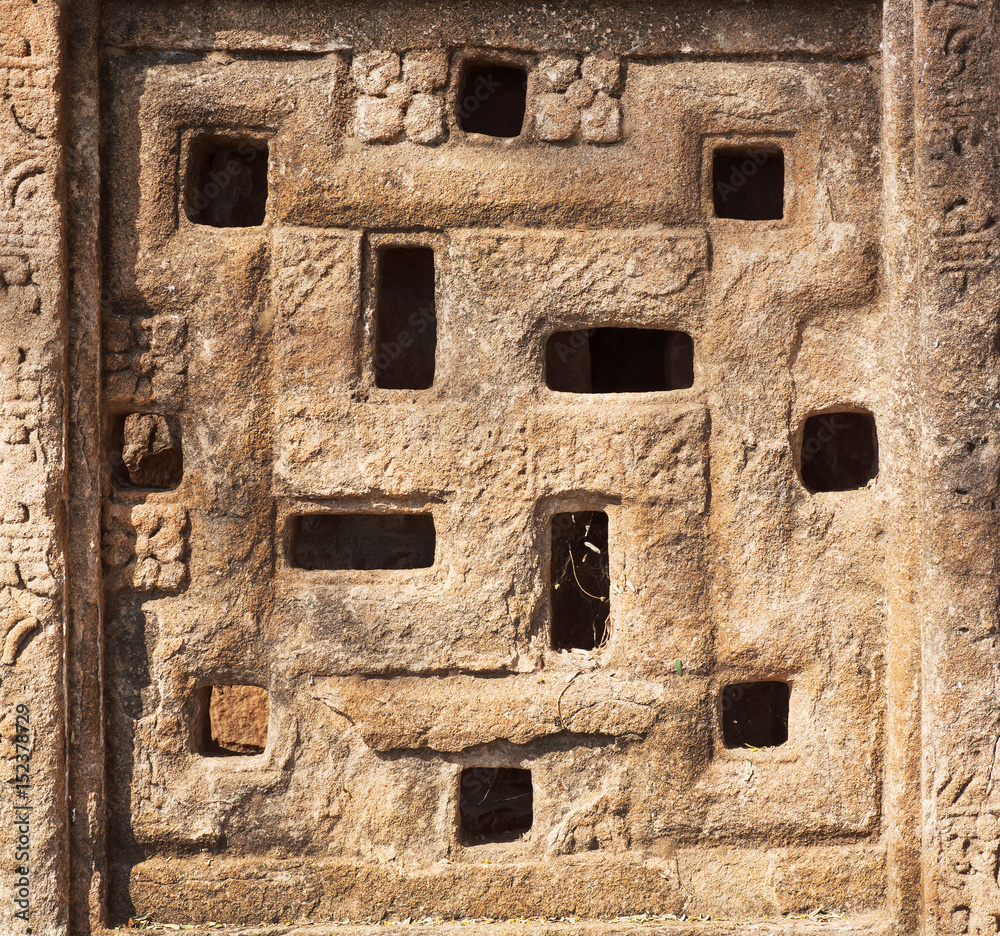 Background with carved swastika sign on Indian rock-cut architecture example. Window of 6th century Hindu temple in town Badami, India
