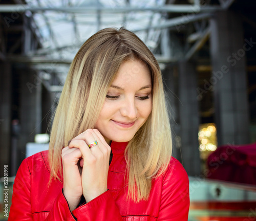 Positive emotional portrait of young beautiful blond woman with red leather jacket