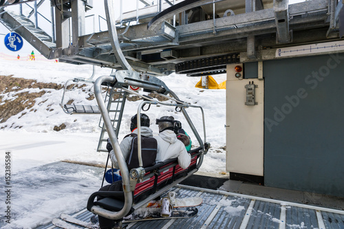 Young people sitting on ski lift with seats in a ski-resort