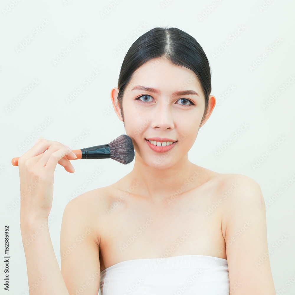 Asian woman Face Portrait Beauty Skin Care and applying cosmetic powder brush on smooth face isolated on white background. Natural makeup, skincare, cosmetology and plastic surgery concept. Asian woman Face Portrait Beauty Skin Care and applying cosmetic powder brush on smooth face isolated on white background. Natural makeup, skincare, cosmetology and plastic surgery concept.